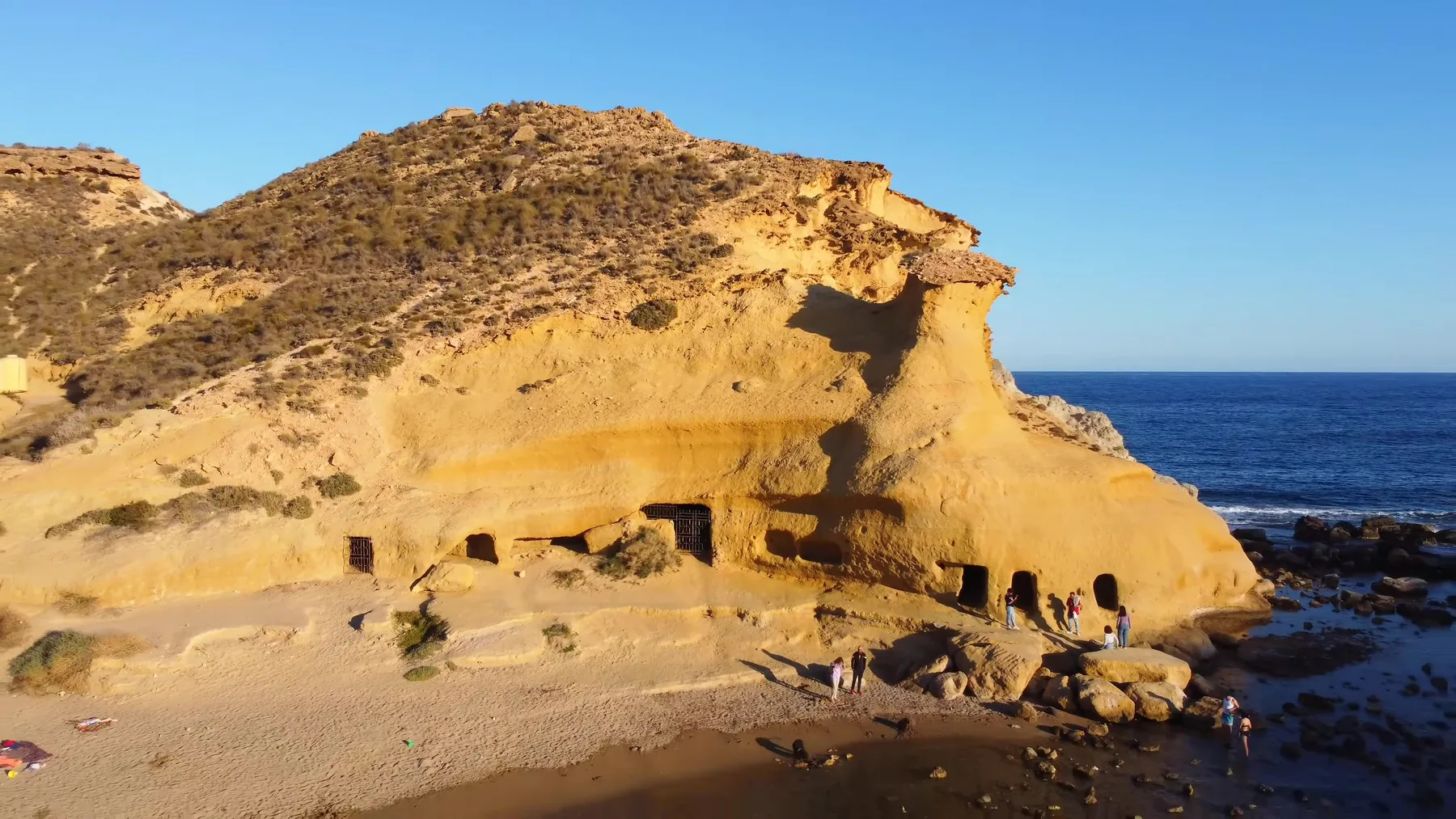 Cuevas excavadas en la roca dorada de la playa de Los Cocedores