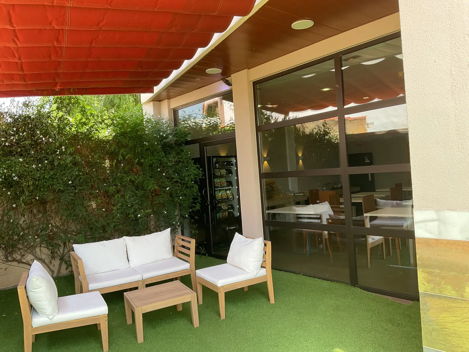 Terraza con sofás bajo el toldo, junto al comedor